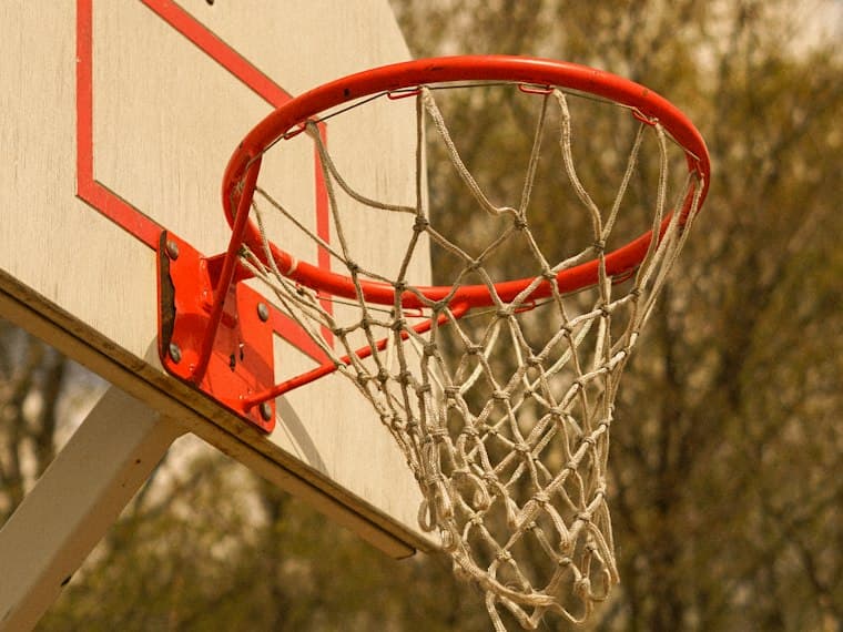 Aro y red de baloncesto al aire libre con luz de tarde.