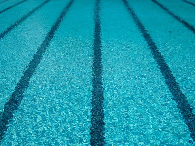 Líneas de carril bajo el agua azul de una piscina.